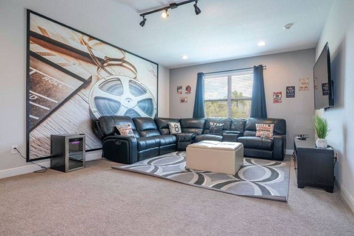 A modern living room with a sectional sofa, a flat-screen TV, and a large abstract painting.