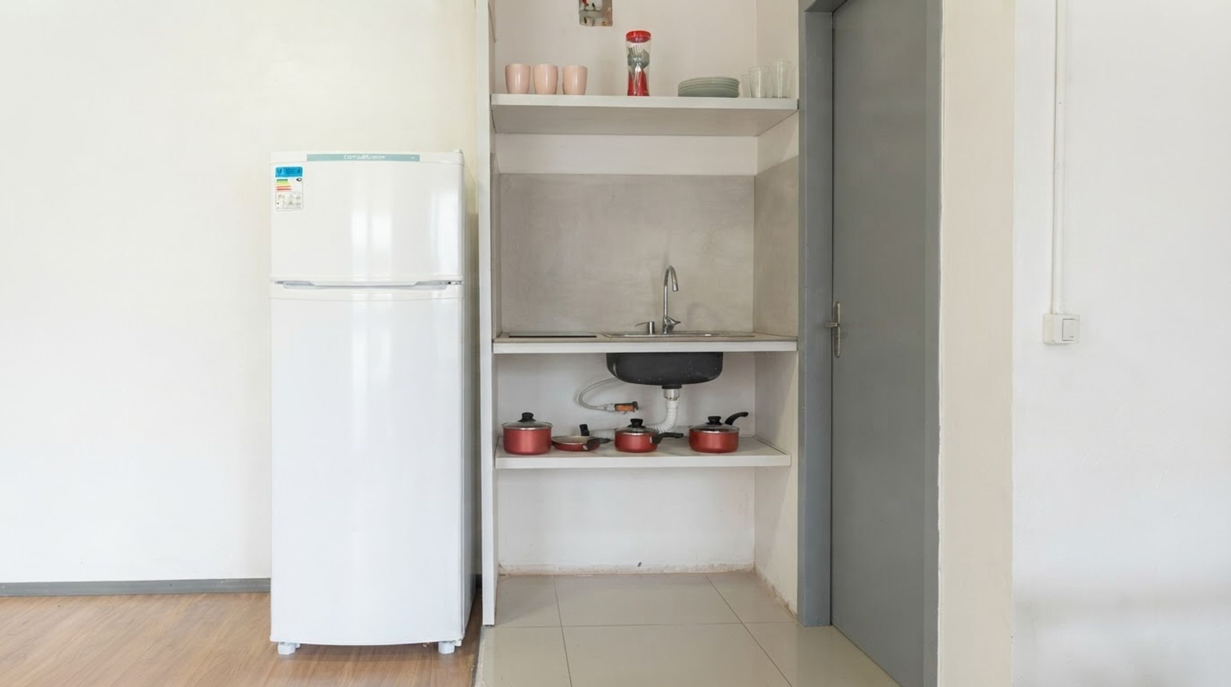 Una cocina compacta con un refrigerador blanco, un lavamanos y una encimera con ollas.