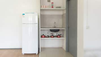 Una cocina compacta con un refrigerador blanco, un lavamanos y una encimera con ollas.