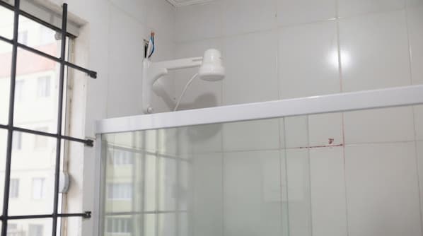 Chuveiro com divisória de vidro e chuveiro embutido no teto, branco.