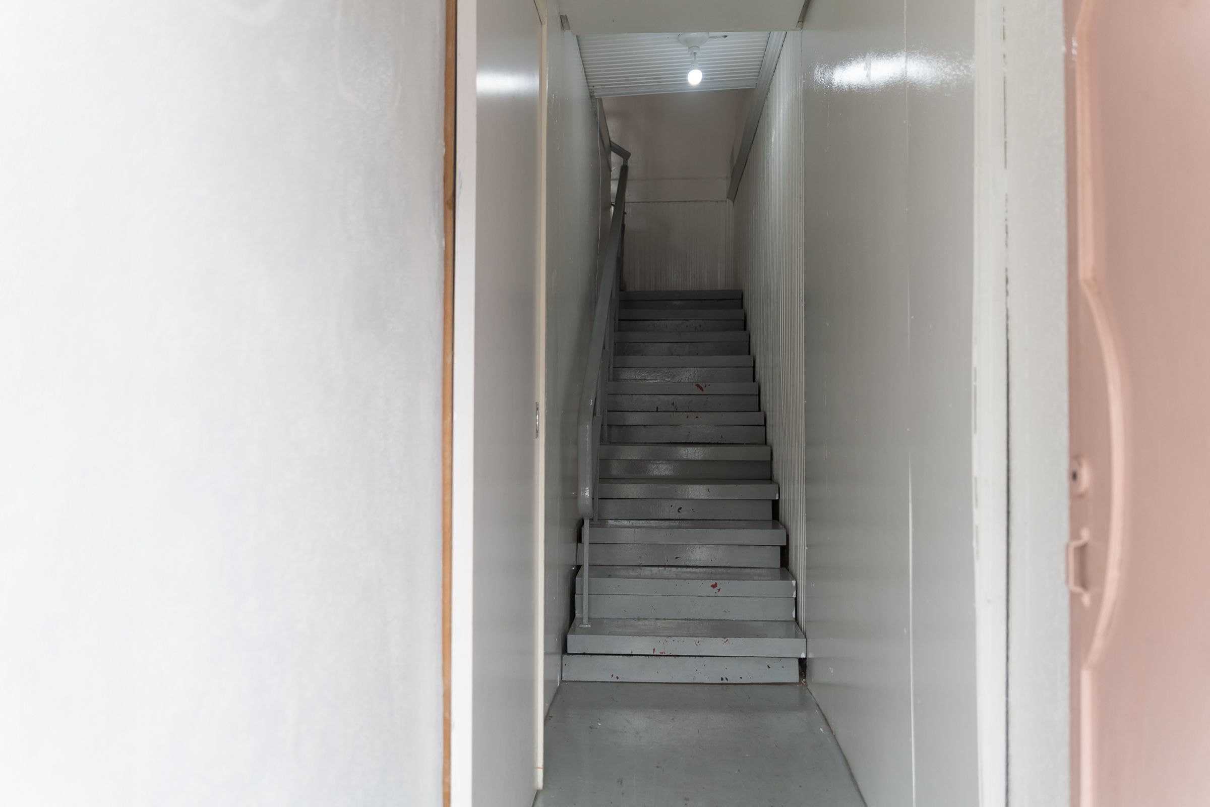 Una escalera estrecha y cerrada con barandilla, que conduce a una plataforma.