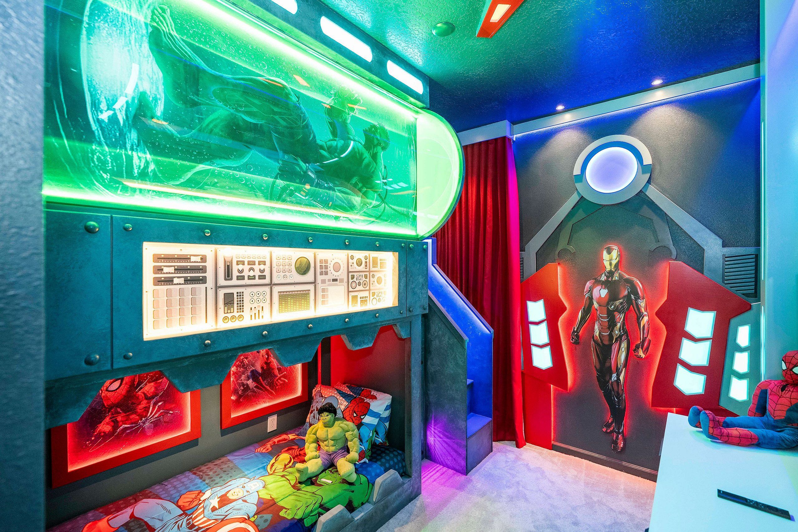 A room with a control panel, a large poster of a superhero, and a plush toy on the floor.