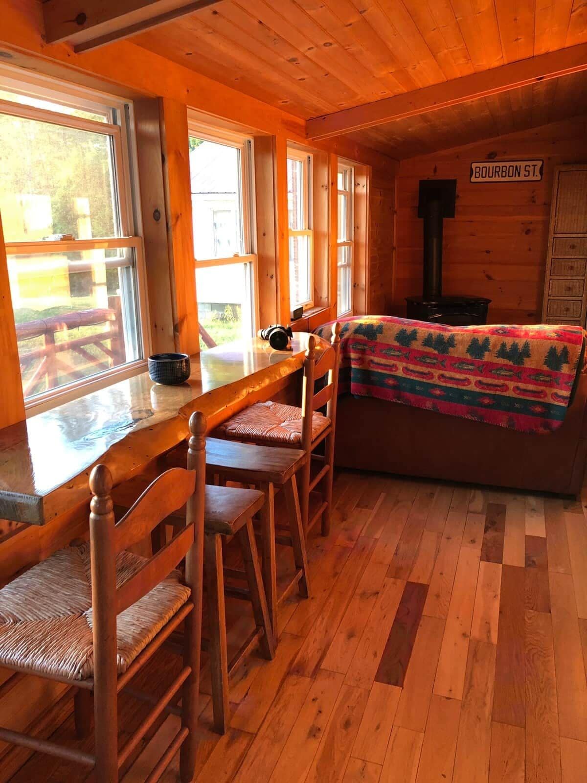 A cabin interior with a wooden dining table, chairs, a sofa, and a fireplace.