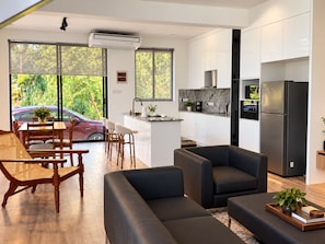 Une cuisine moderne dotée d’un réfrigérateur encastré, un coin repas avec une table et des chaises en bois, et un espace détente avec des canapés.