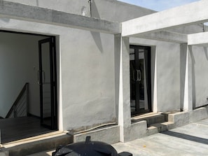 Een modern gebouw met een betonnen buitenkant, een trap die naar een ingang leidt, en een glazen deur.