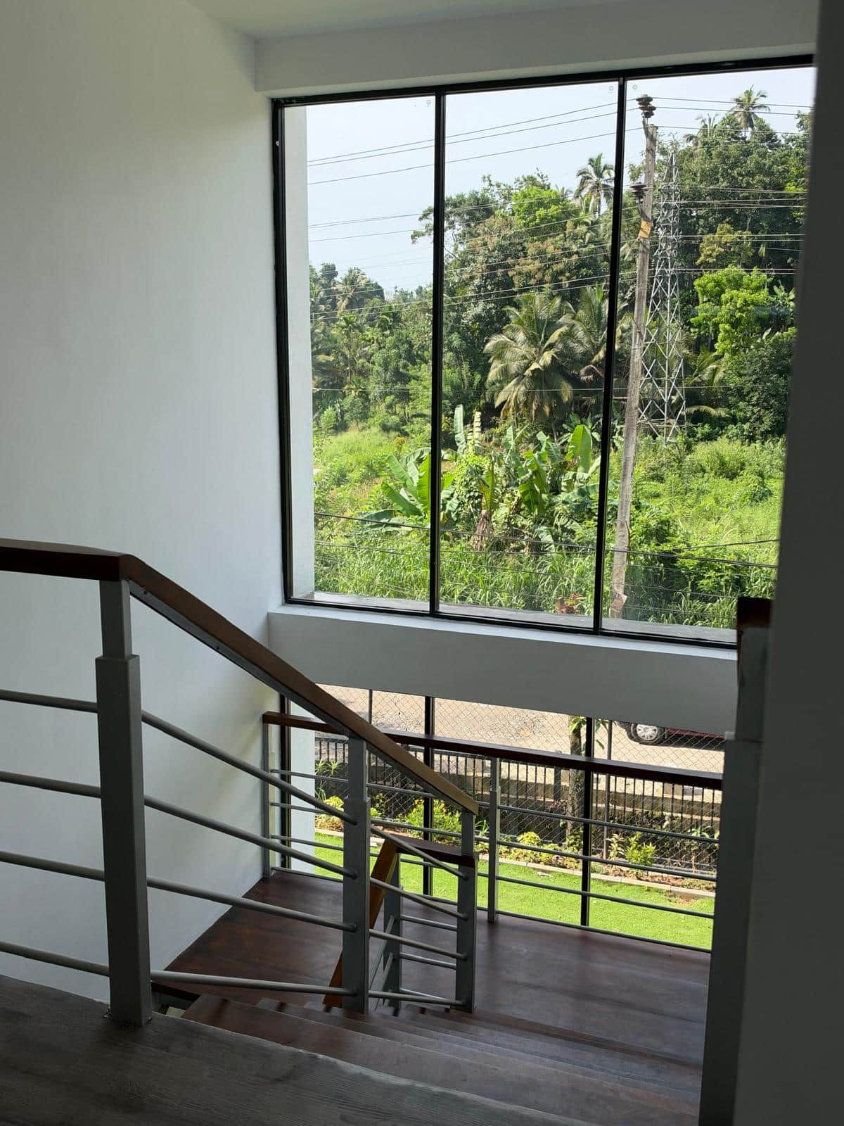 Una scala conduce a un balcone da cui si gode una vista su un paesaggio verde e rigoglioso, con palme.