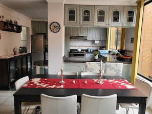 Ein Essbereich mit rotem Tischläufer, weißen Stühlen und einer Uhr an der Wand.