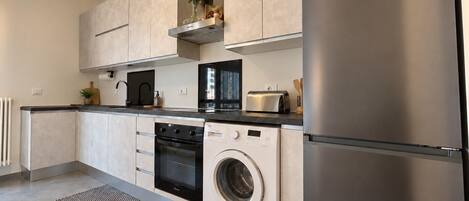 A modern kitchen with stainless steel appliances, a built-in oven, microwave, and dishwasher, and a large refrigerator.