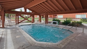 Una piscina coberta amb un pont de fusta i seients per relaxar-se.