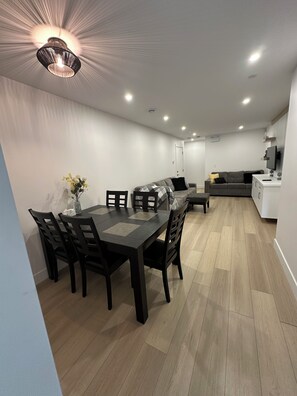 Une cuisine moderne avec un coin repas, comprenant une table et des chaises en bois, un canapé et un téléviseur.