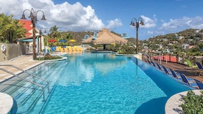 A clear blue pool with a wooden deck, lounge chairs, and a thatched-roof structure. - Margaritaville Vacation Club St. Thomas - Ocean View Studio Suite (Eastend)