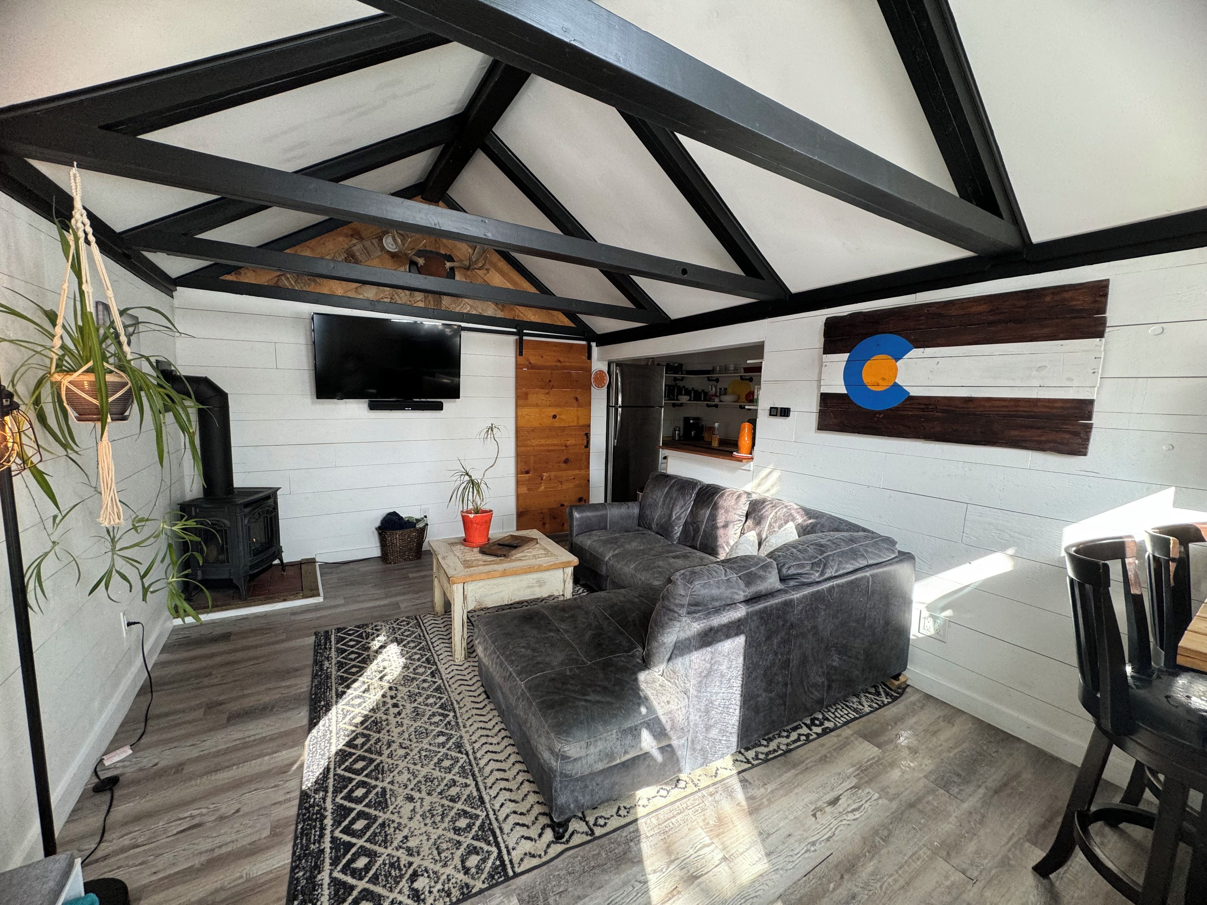Un salon moderne avec un canapé d’angle, un téléviseur à écran plat, une cheminée et un mur décoratif en bois.