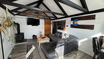 Un salon moderne avec un canapé d’angle, un téléviseur à écran plat, une cheminée et un mur décoratif en bois.