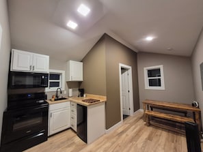 A compact kitchen with white cabinets, a black microwave, and a built-in oven. - Private ATV Cabin Near Ivy Branch & Outlaw Trails (Alkol)