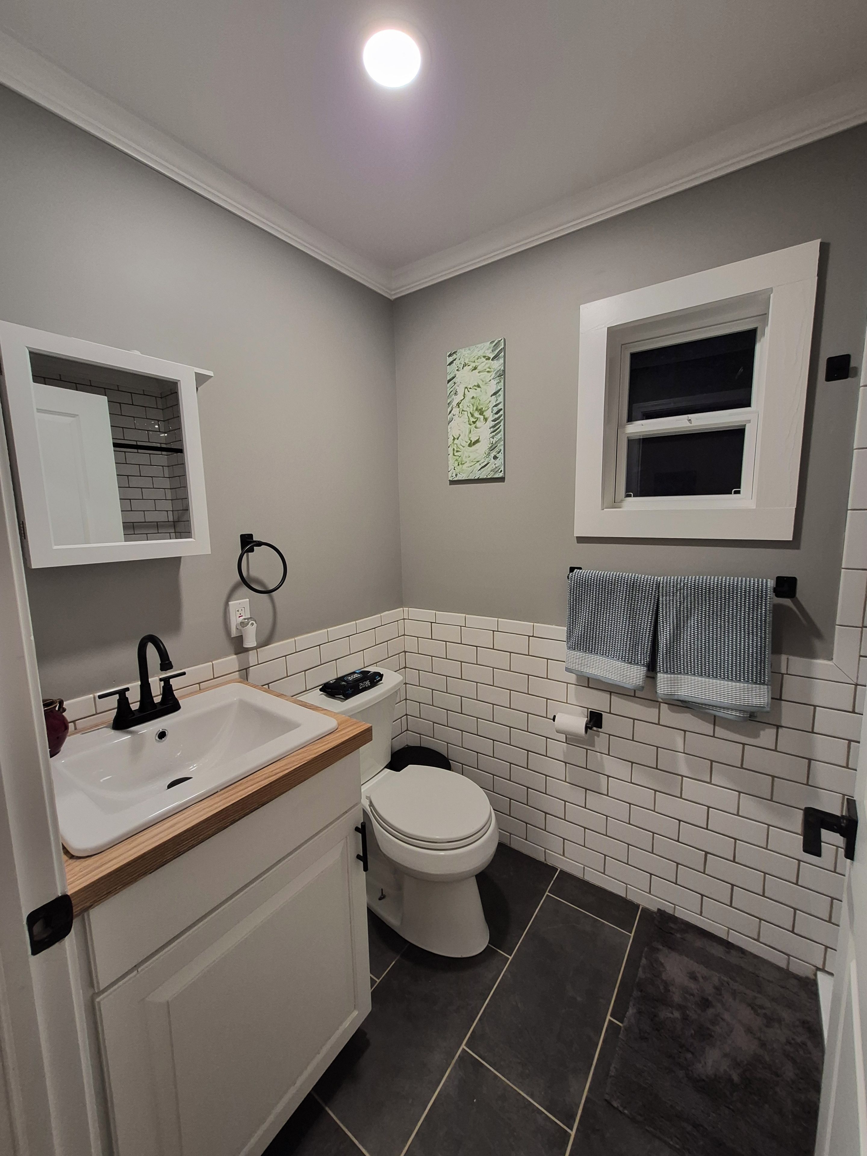 A bathroom with a white sink, a toilet, a towel rack, and a window.