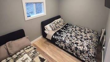 A bedroom with a bed, a window, and a wall-mounted TV.