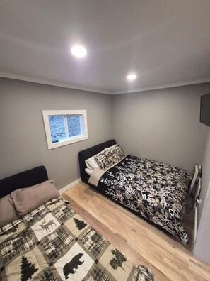Un dormitorio con cama, ventana y televisor montado en la pared.