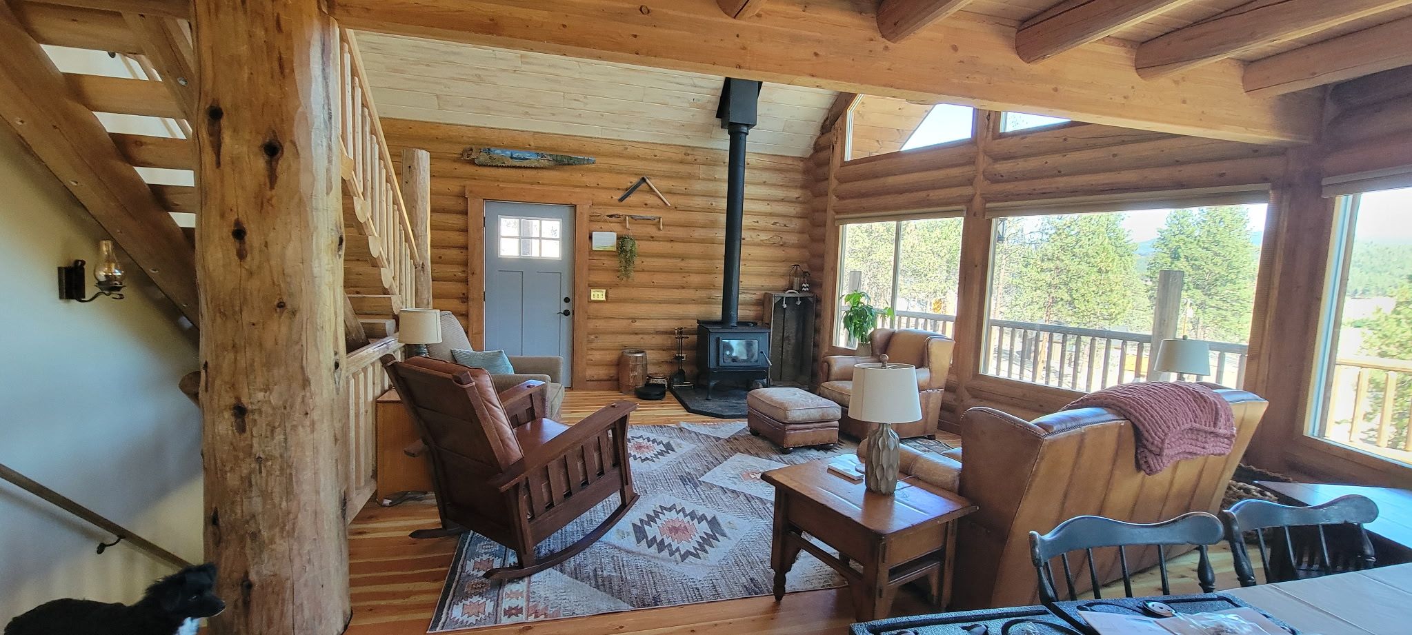 Un interior acogedor de cabaña con chimenea, muebles de madera y vistas al exterior.