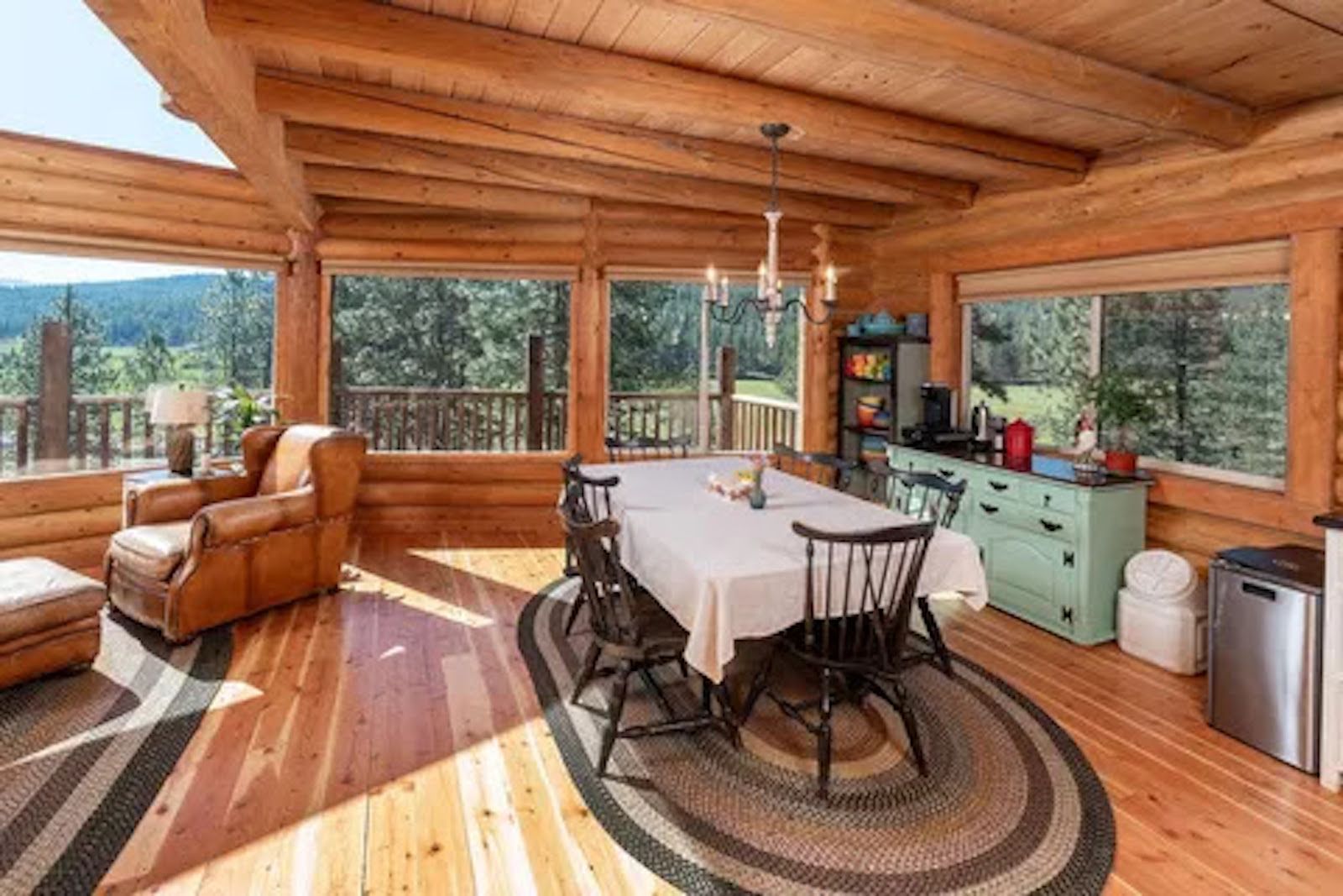 L’intérieur d’une cabane en rondins comprend un coin repas, des sièges et offre une vue sur l’extérieur.