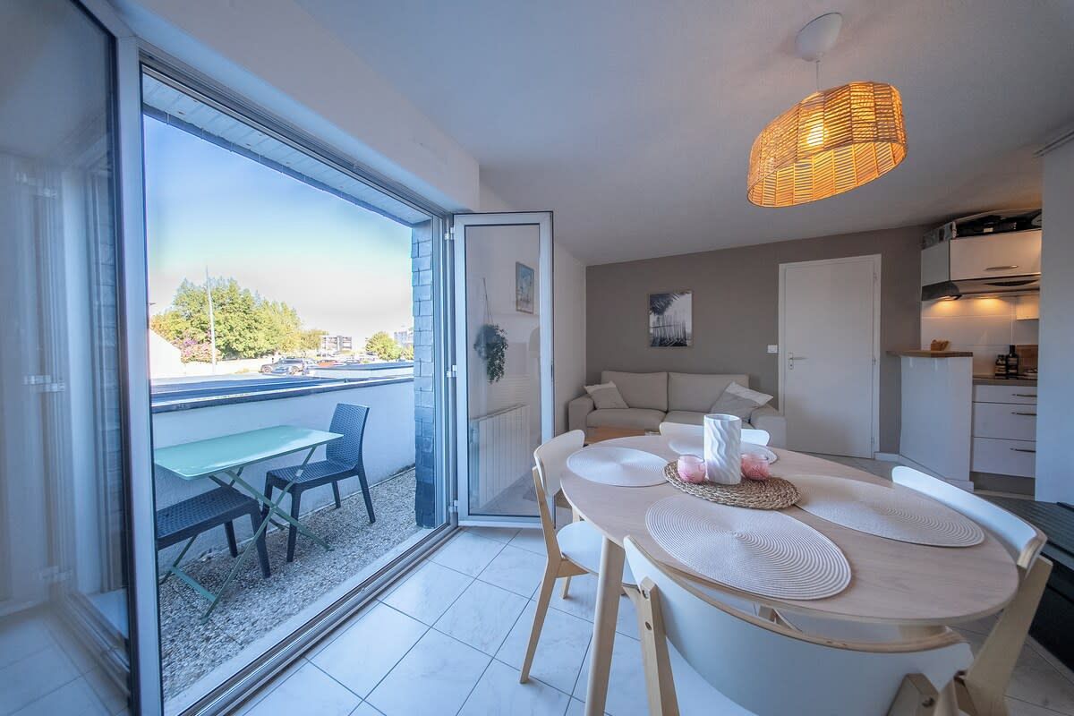Un apartamento moderno con comedor, cocina y puerta corrediza de vidrio que da a un patio exterior.