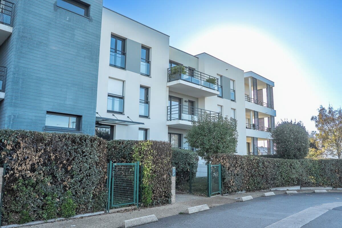 Un edifici residencial de diversos pisos amb balcons, una entrada tancada amb reixa i una tanca ben cuidada.