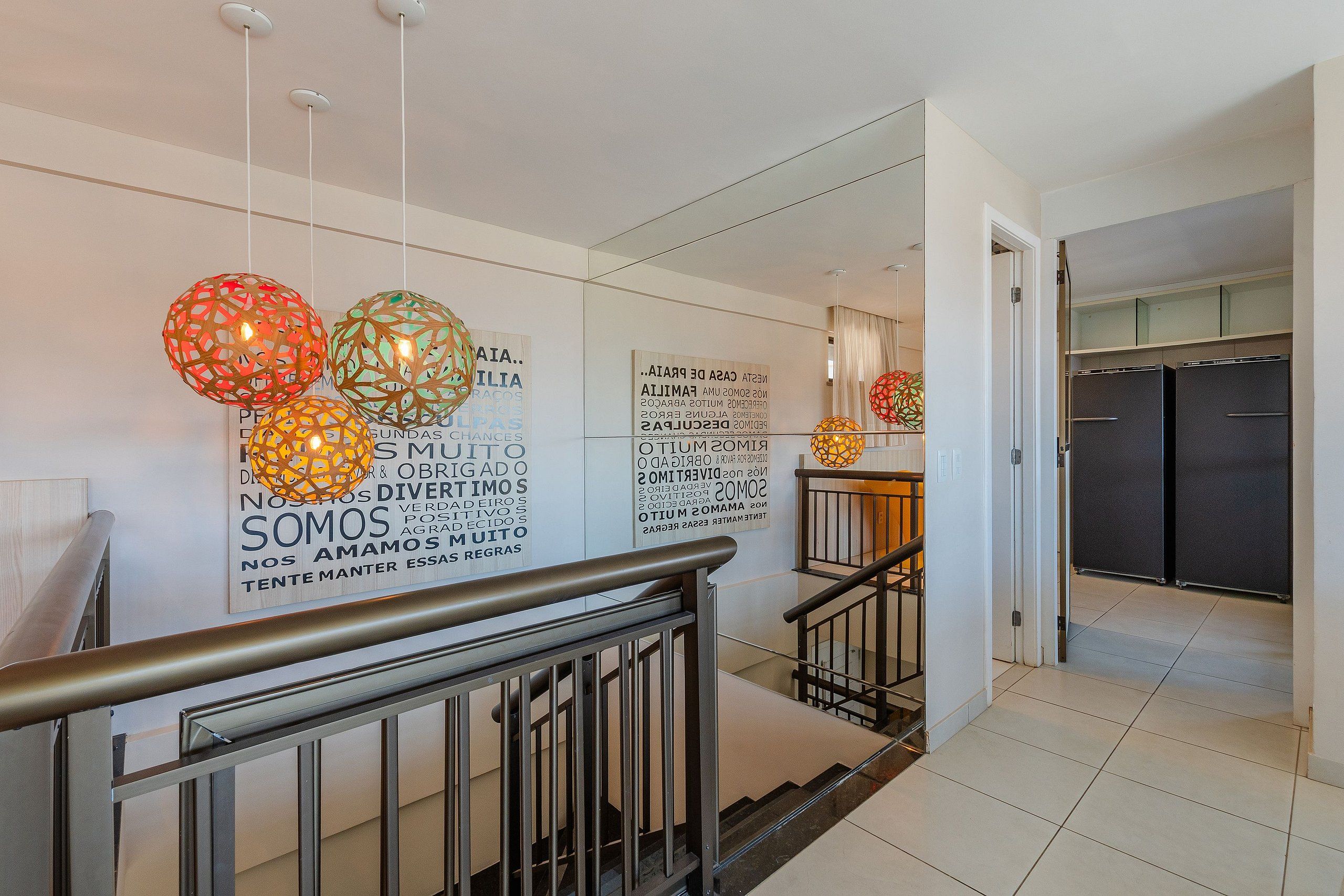 Interior moderno com escada, luminárias esféricas decorativas e uma parede com mensagens motivacionais.