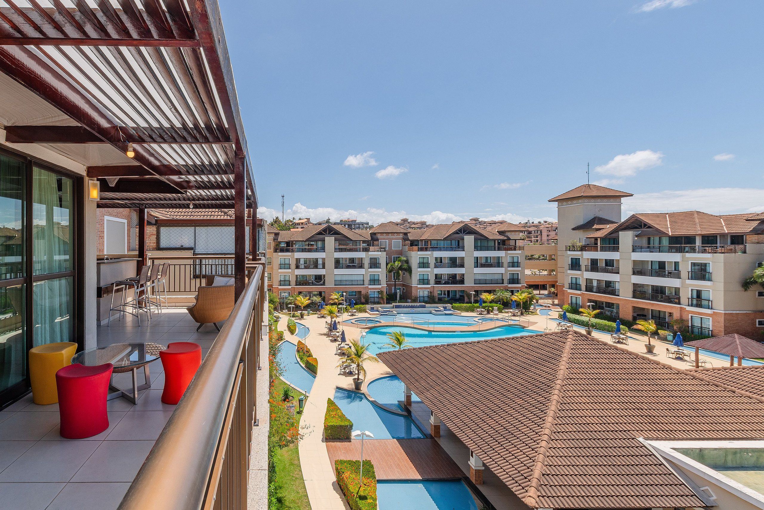 Hotel com piscina no terraço, várias varandas e vista para outros edifícios.