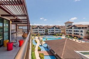 Hotel com piscina no terraço, várias varandas e vista para outros edifícios.