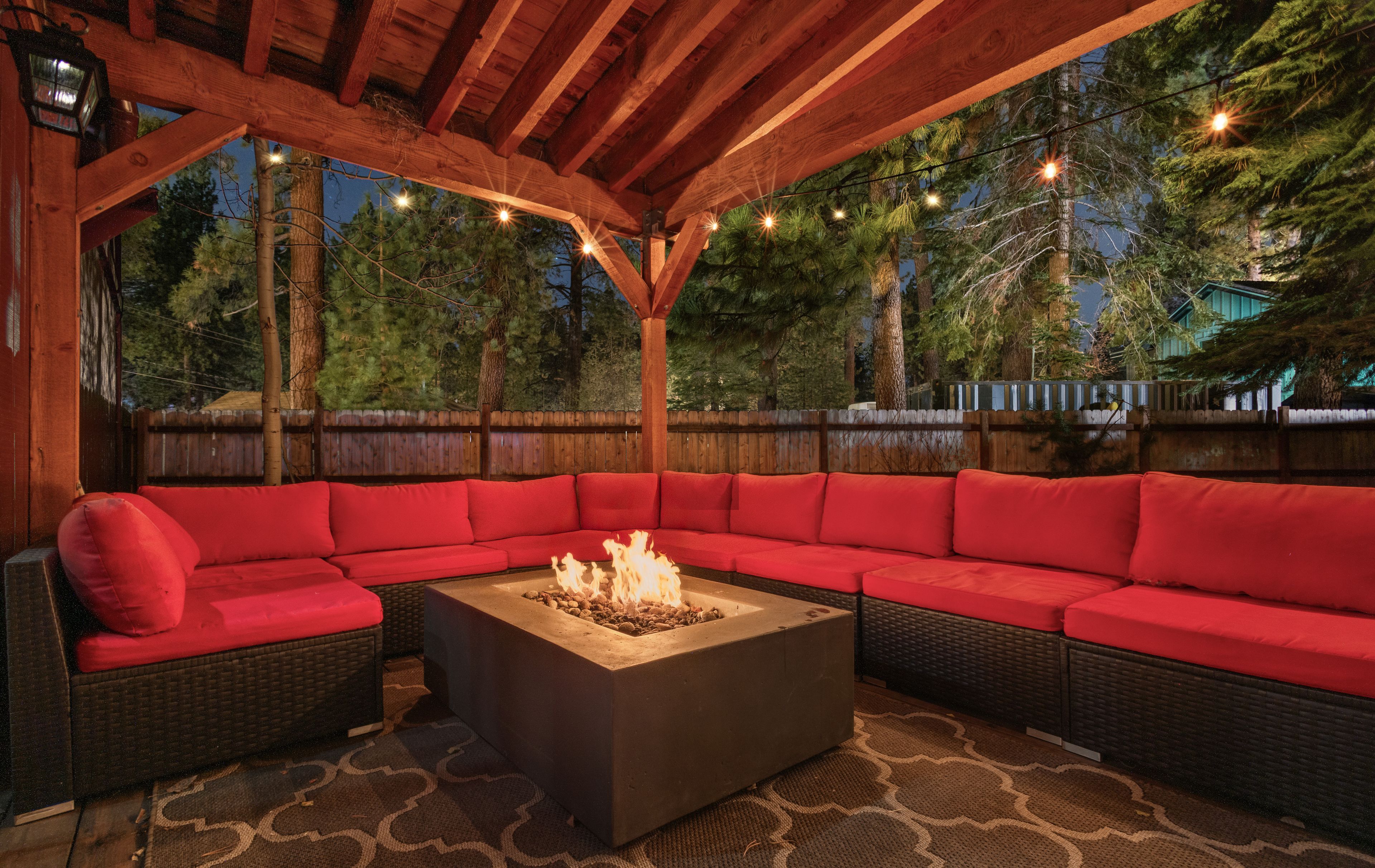 An outdoor seating area with a fire pit and red cushions.