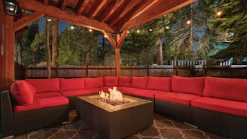 An outdoor seating area with a fire pit and red cushions.