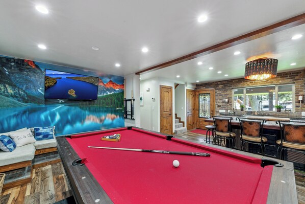 A pool table with a red felt surface, a pool cue, and a white cue ball.
