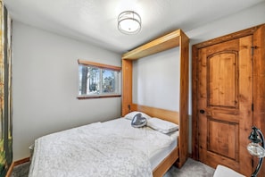 Un dormitorio con cama, ventana, puerta y lámpara.