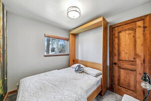 Un dormitorio con cama, ventana, puerta y lámpara.