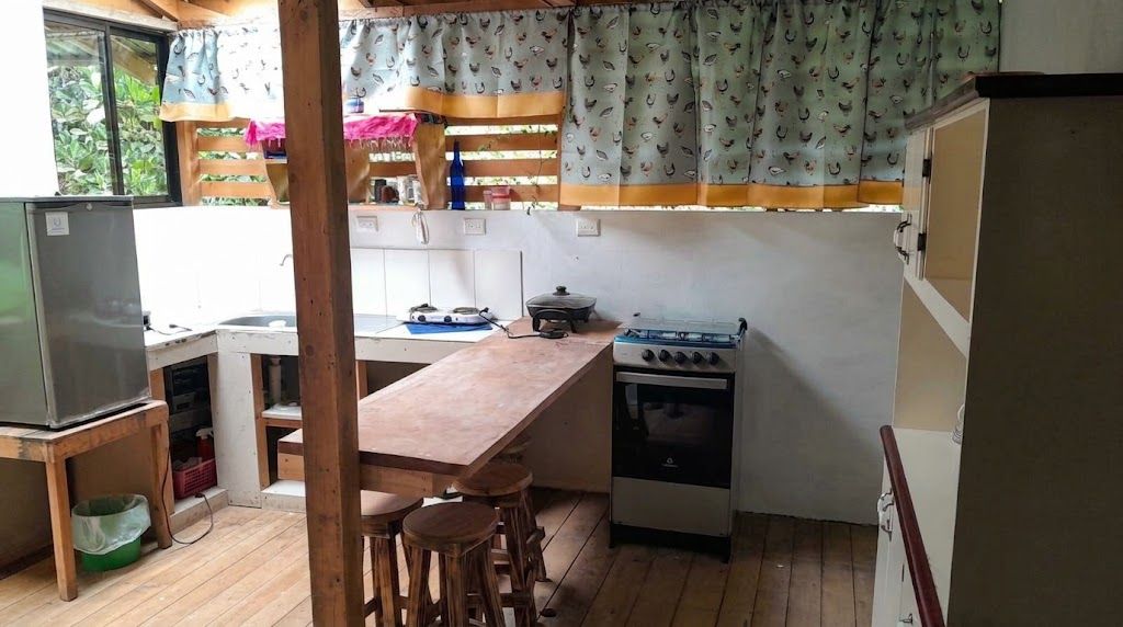 Eine kleine Küche mit Holztisch, Barhocker, Gasherd und Kühlschrank.