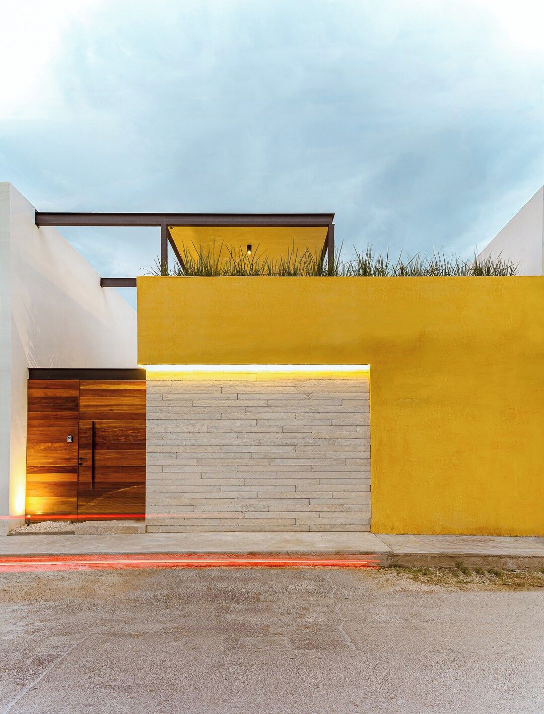 Un bâtiment moderne avec une façade jaune, une porte en bois et une porte de garage.