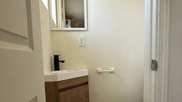 A small bathroom with a toilet, a sink, and a mirror.