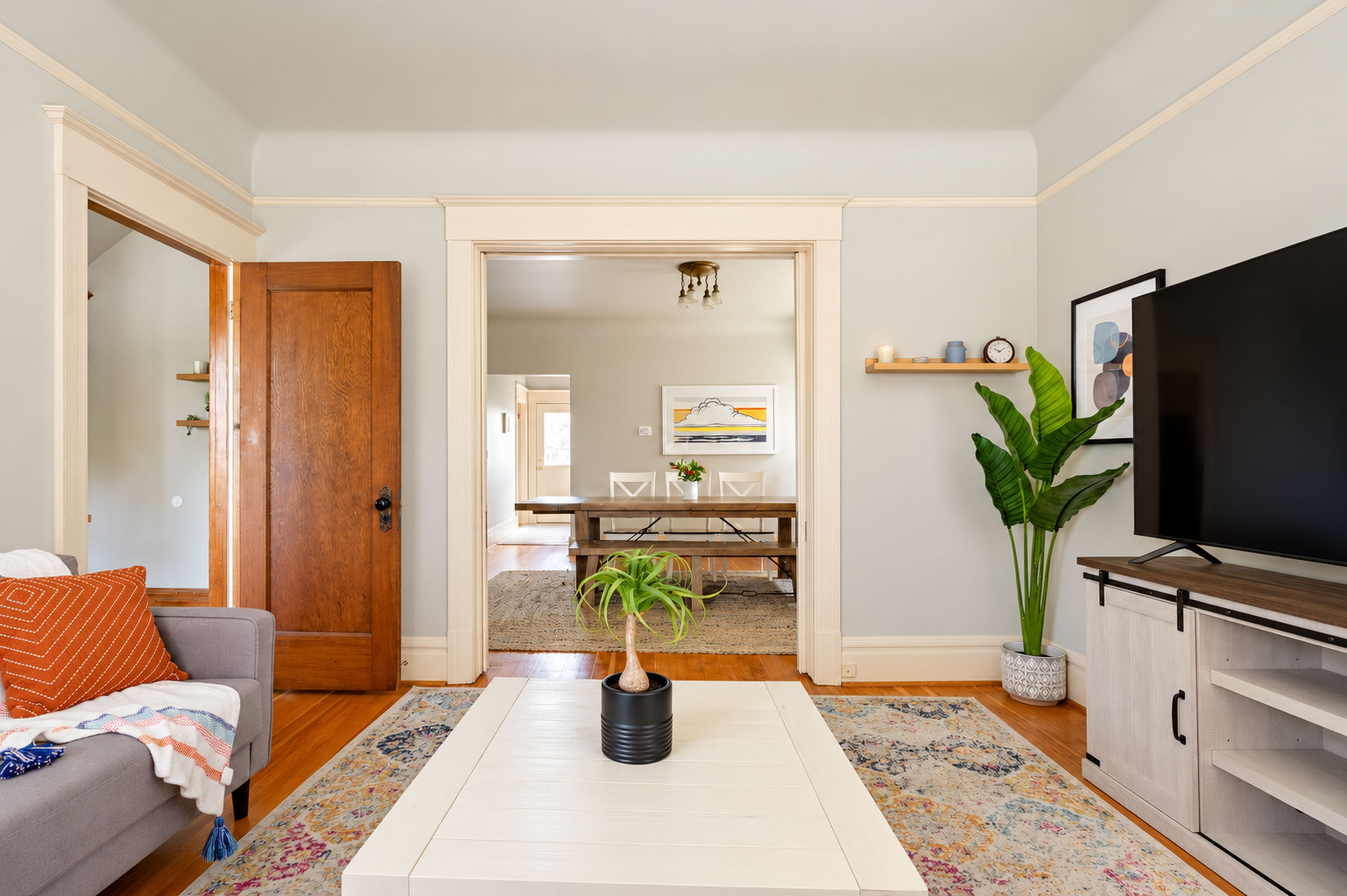 Bright living room with smart TV, hardwood floors, and open dining flow