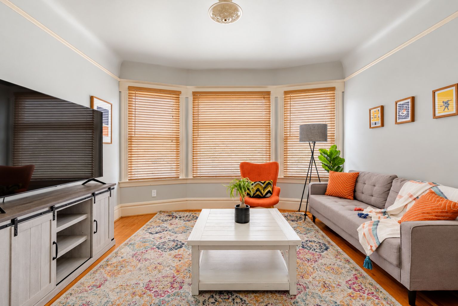 Bright, stylish living room with bay windows, large TV, and cozy seating