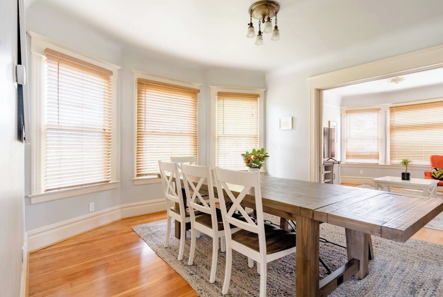 A dining area with a wooden table, white chairs, and a chandelier.