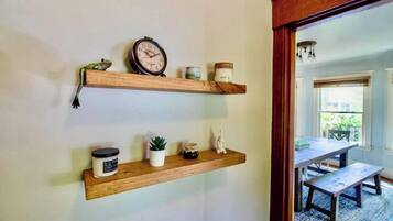 A hallway with two wooden shelves, each holding various items like a clock, candles, and small plants.