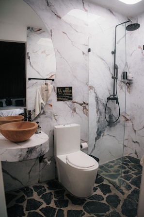 A bathroom with a marble wall, a wooden bowl sink, a toilet, and a shower. - Bliss Club (El Peñol)