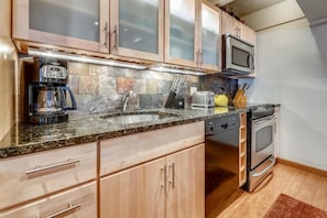Una cocina con encimeras de granito, electrodomésticos de acero inoxidable y armarios de madera.