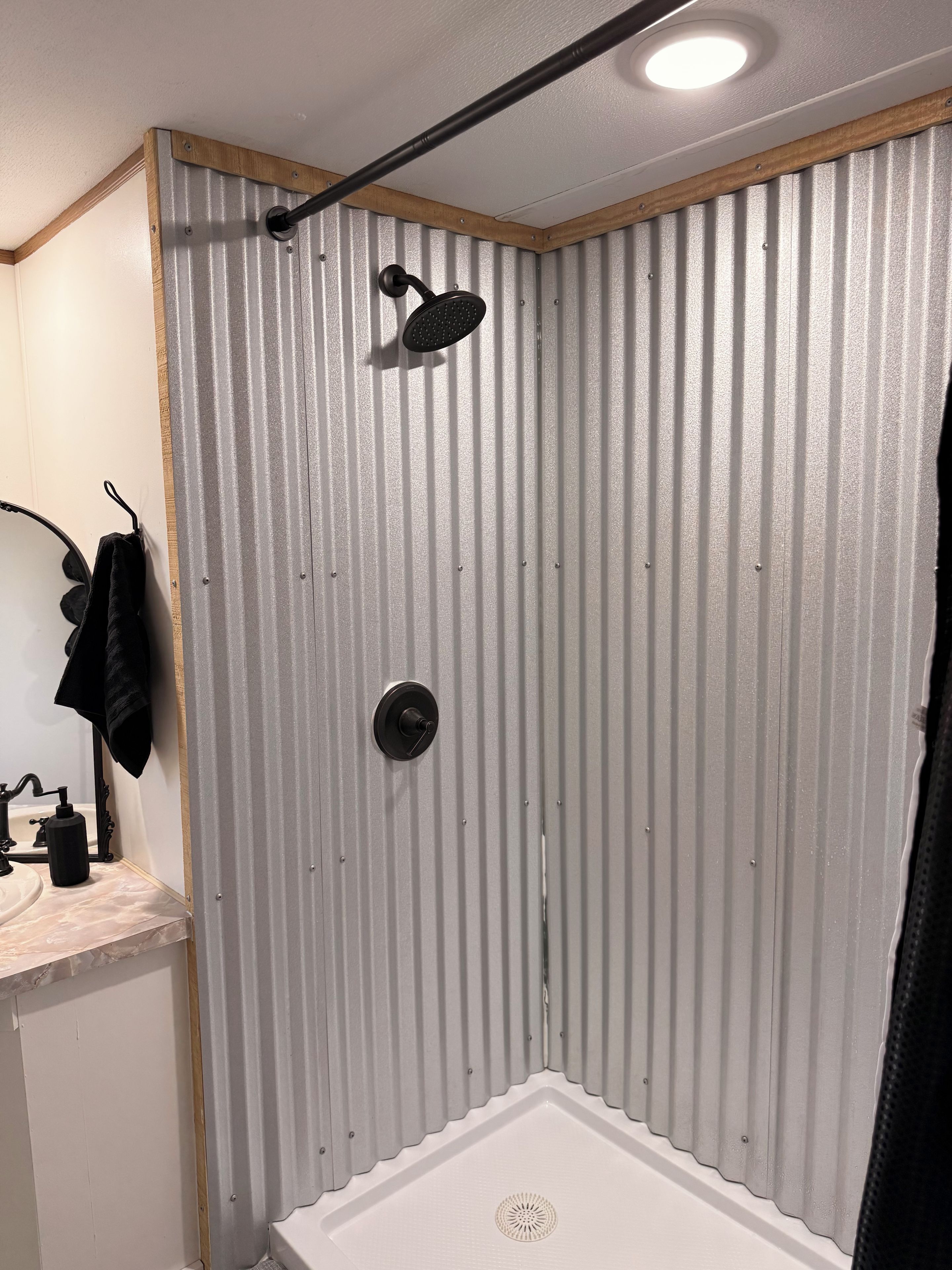 Eine Dusche mit Regendusche, einem Handtuchhalter und einem weißen Waschbecken mit Marmorplatte.