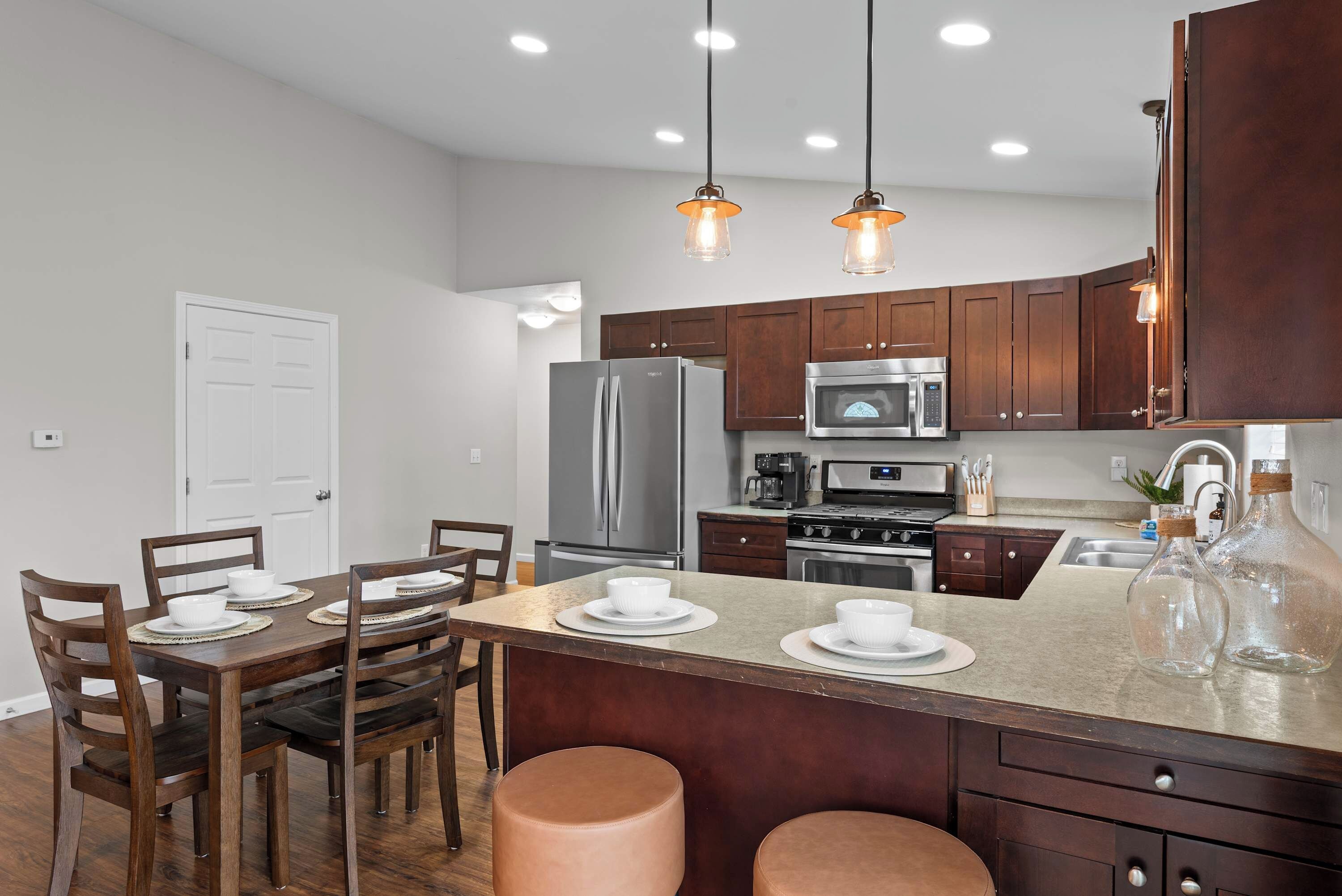 A modern kitchen with stainless steel appliances, wooden cabinets, and pendant lighting.