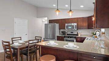 A modern kitchen with stainless steel appliances, wooden cabinets, and pendant lighting.