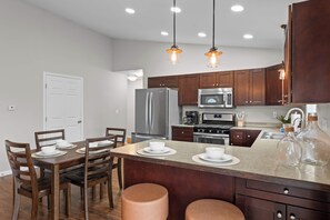 Una cocina moderna con electrodomésticos de acero inoxidable, armarios de madera e iluminación colgante.