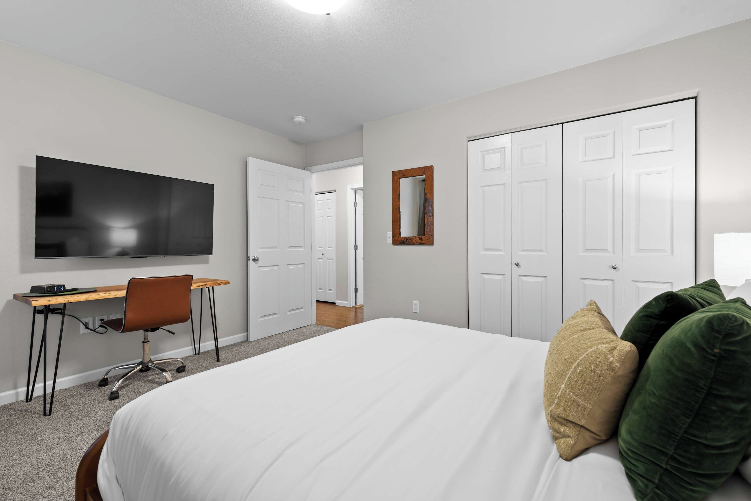 A hotel room with a bed, a desk, a television, and a wardrobe.