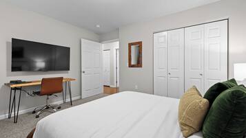 A hotel room with a bed, a desk, a television, and a wardrobe.