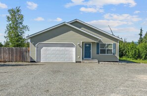 A single-story house with a garage, a front door, and a small porch. - Quiet 3BR Getaway w/ Full Kitchen & Laundry! (Wasilla)