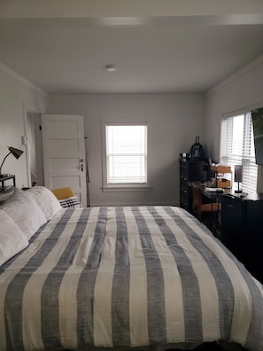 Une chambre à coucher avec un lit, un bureau, une chaise, une fenêtre et une porte.